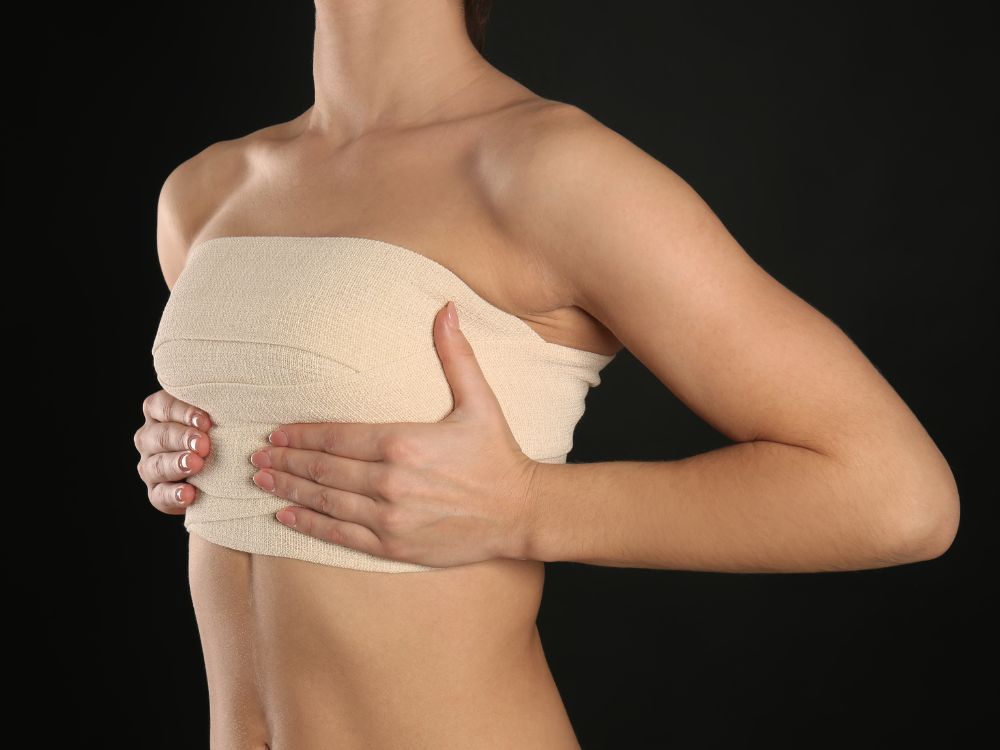 Paciente com faixa de compressão no tórax no período pós-operatório para explicar o que é mamoplastia.