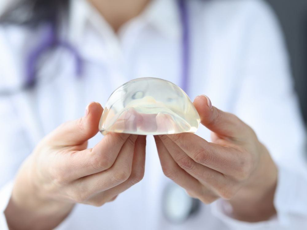 Médica demonstra prótese de silicone em ambiente clínico durante explicação técnica sobre se a doença do silicone existe.