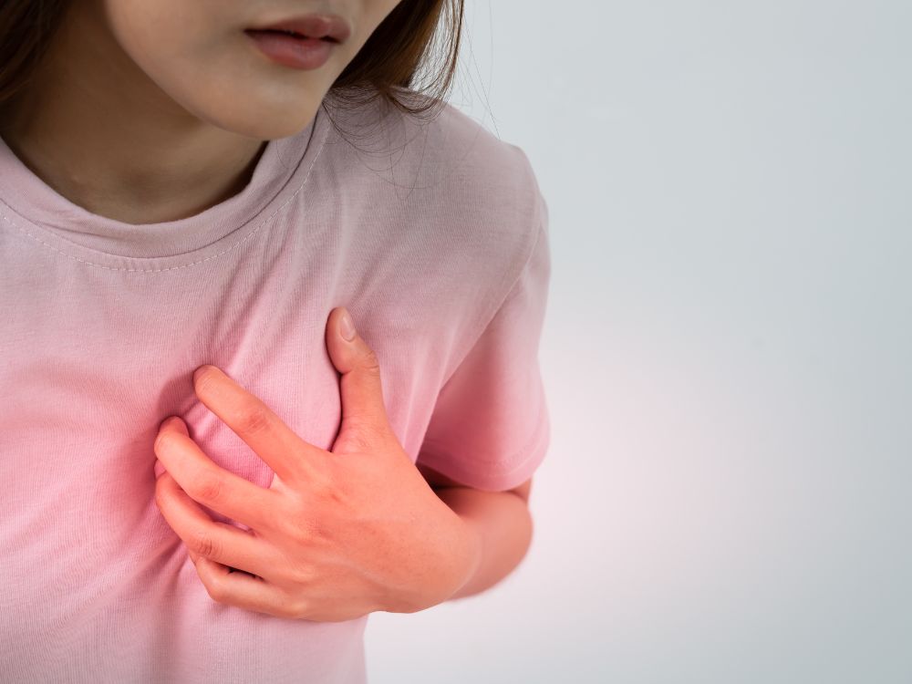 Mulher pressionando o lado do seio devido à dor localizada, associada a fisgadas na mama após cirurgia.