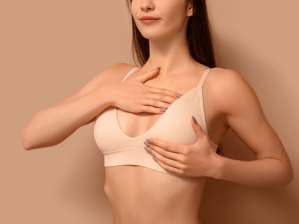 Mulher usando sutiã cirúrgico após procedimento, indicando quanto tempo de repouso da mamoplastia e os cuidados no pós-operatório.