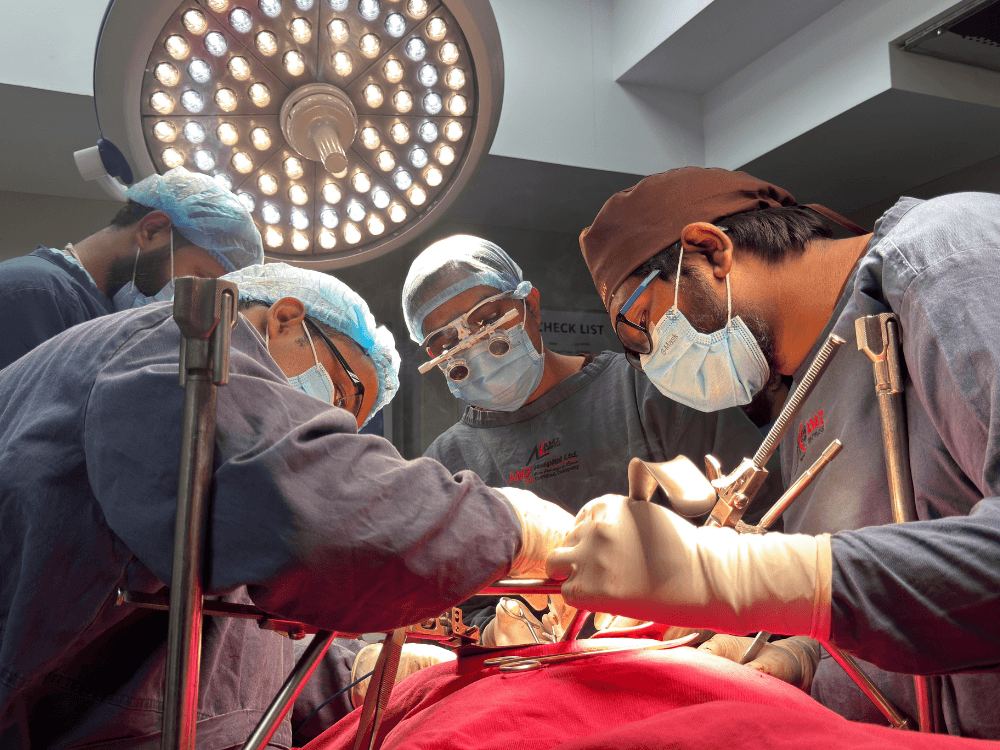 Equipe médica realiza um procedimento cirúrgico em centro cirúrgico, utilizando máscaras, luvas e instrumentos sob iluminação especializada.