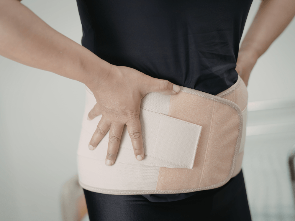 Pessoa utilizando faixa abdominal compressiva no pós-operatório, um recurso que pode ser indicado conforme o tipo de cirurgia e avaliação médica. Tudo para explicar seroma o que é.